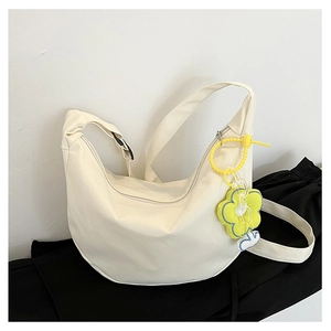 Détail du sac demi-lune en toile beige avec zip argenté et breloque fleur jaune