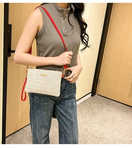 Détail du sac bandoulière tressé beige et rouge avec bandoulière amovible sur modèle
