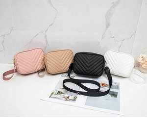 Detail view of four candy-colored quilted crossbody camera bags with V-shaped stitching