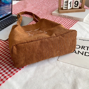 Simpatica borsa tote in velluto a coste marrone con ricamo su sfondo stile di vita