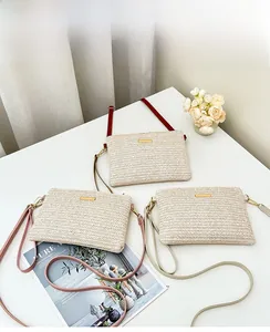 Macro shot of V-shaped straw weave texture and gold metal clasp on envelope crossbody bag