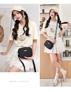 Detail view of black quilted crossbody bag with golden metal decor and wide fabric strap