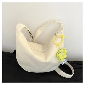Détail du sac croissant en toile blanche avec bandoulière large et breloque fleur jaune