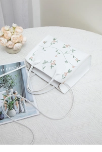 Detail of floral embroidery on a white leather mini handbag with a lifestyle setup