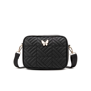 Minimalist black quilted crossbody bag with white butterfly charm and wide shoulder strap