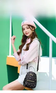 Outdoor model display of a black mini backpack with pink floral and bow pattern prints
