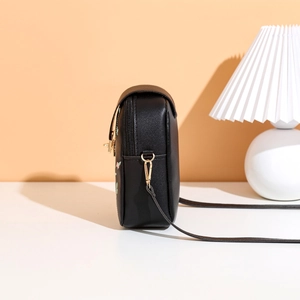 Detail view of smooth zipper and gold hardware on embroidered black crossbody phone bag