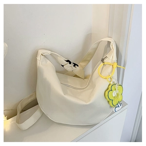 Détail du sac demi-lune en velours côtelé blanc cassé avec breloque fleur et zip argenté
