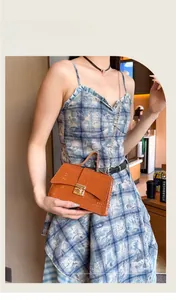 Detail of orange crocodile pattern handbag with gold twist lock and chain strap