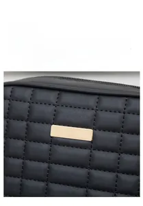 Close-up of black quilted camera bag featuring matte texture and gold metal plaque detail