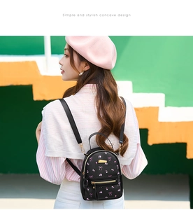 Mini floral PU leather backpack worn by model against a colorful step wall background