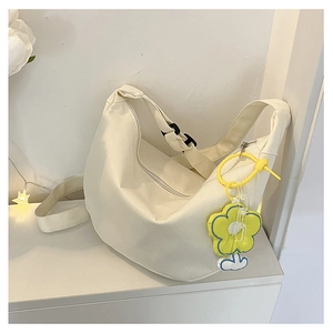 Détail du sac hobo demi-lune crème minimaliste avec bandoulière réglable et breloque fleur