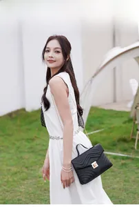 Outdoor model display of a black chevron quilted shoulder bag with golden metal hardware