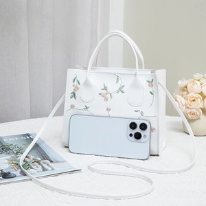 White tote bag with floral embroidery and detachable strap shown with a smartphone