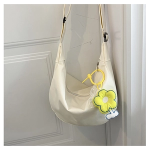 Détail d'un sac bandoulière demi-lune blanc crème avec un pendentif fleur de tournesol