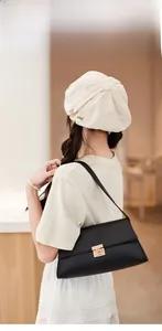 Détail du sac baguette noir en cuir grainé avec fermoir doré porté par le modèle