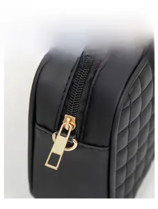 Close-up of smooth gold metal zipper and black quilted faux leather handbag texture