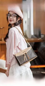 Detail of printed shoulder bag with metal logo, dual tassels, and adjustable strap