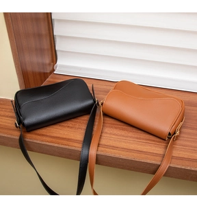 Gros plan de sacs à bandoulière en cuir mat noir et marron avec rabats et boucles dorées
