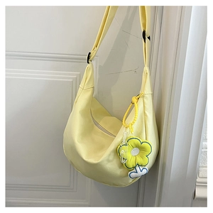 Détail du sac demi-lune en toile jaune clair avec un adorable accessoire de fleur jaune