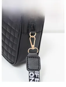 Macro shot of black quilted faux leather crossbody bag with gold-tone metal hardware