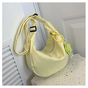 Détail du sac bandoulière demi-lune jaune clair en velours avec pendentif fleur