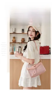 Detail of light pink quilted crossbody bag with metal nameplate and delicate strap