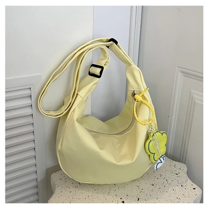 Détail du sac hobo en tissu jaune avec breloque fleurie sur socle en pierre