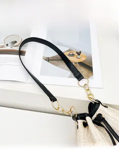 Dettaglio della borsa a secchiello intrecciata con tracolla in pelle nera e catena d'oro