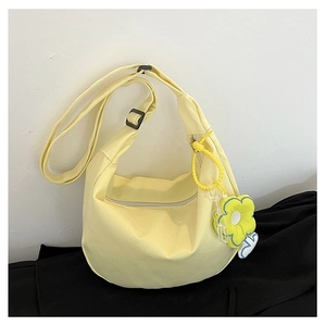 Détail du sac croissant en toile jaune clair avec breloque fleurie et sangle