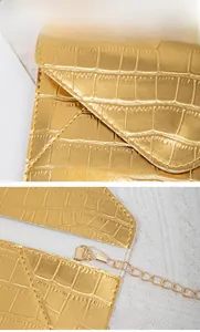 Detail view of gold crocodile embossed leather texture with fine stitching and metal chain