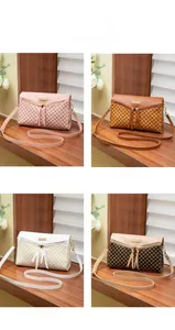 Detail of cross-body bags in pink, brown, and white with dual tassel and geometric texture