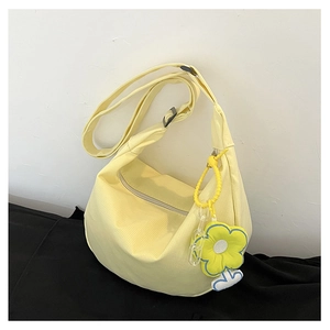 Détail du sac bandoulière en toile jaune avec sangle réglable et breloque fleur