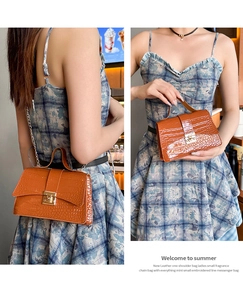 Detail showing orange croc-embossed handbag with gold chain strap and turn-lock closure