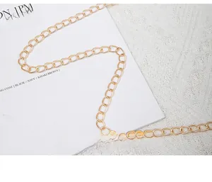 Detail of elegant gold metal chain strap on textured leather envelope clutch bag