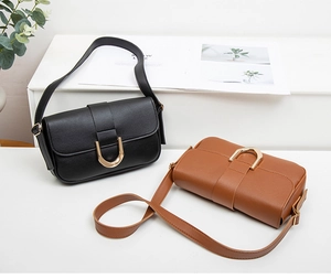 Detailansicht der Lederschultertaschen mit goldener Hufeisenschnalle in Schwarz und Karamell