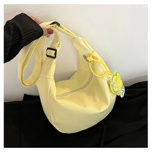 Détail du sac demi-lune en toile jaune clair montrant la sangle et le pendentif fleur jaune