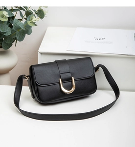 Detail der schwarzen Achseltasche aus genarbtem Leder mit modischer goldener U-Metallschnalle