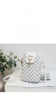 Close-up of white crossbody phone bag with M-pattern print and golden cat-ear metal ring