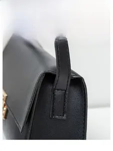 Détail macro d'un sac à bandoulière noir en cuir grainé avec boucle dorée et surpiqûres
