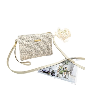 Minimalist cream woven straw crossbody bag with golden zipper and adjustable leather strap
