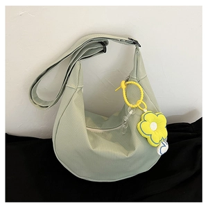 Détail d'un sac demi-lune en velours côtelé vert menthe avec un charme de fleur jaune