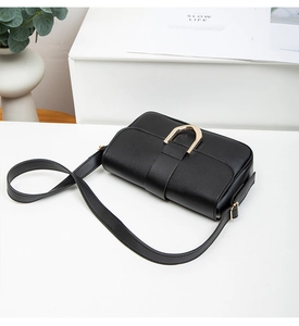 Detailaufnahme einer schwarzen Lederklapptasche mit goldener D-förmiger Metallschnalle