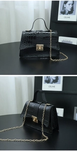 Macro detail of black crocodile embossed handbag with gold hardware and chain strap