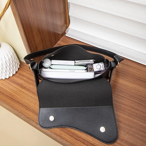 Sac bandoulière noir classique montrant l'intérieur spacieux pour téléphone et maquillage
