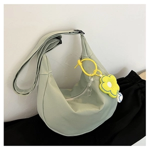 Détail du sac croissant vert menthe avec texture quadrillée, bandoulière et fleur jaune