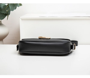 Detailansicht der schwarzen Ledertasche mit Lychee-Muster und goldenen Metallschnallen