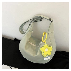 Détail d'un sac à bandoulière demi-lune vert clair avec un pendentif fleur jaune