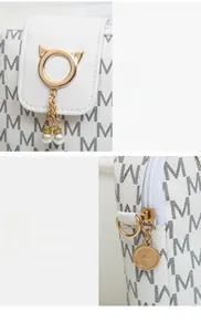 Detail of white monogram handbag with golden cat-ear ring, pearls and metal zipper