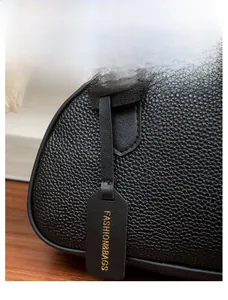 Close-up of black lychee grain leather handbag with gold-embossed fashion bag charm